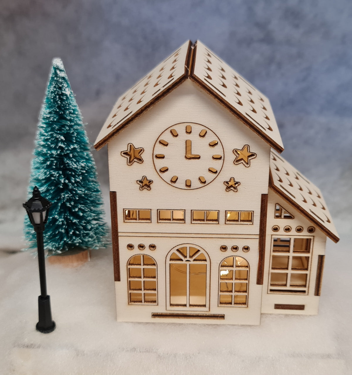 A wooden Christmas model of a house featuring a clock, showcasing intricate craftsmanship and design details.