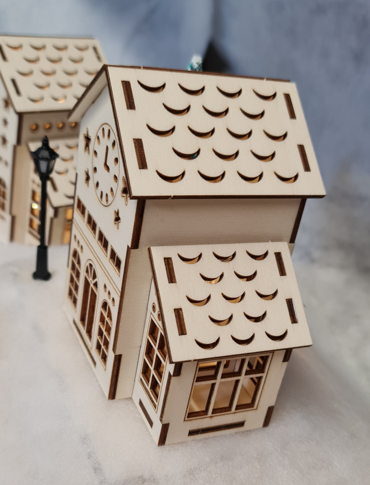 A wooden Christmas model of a house featuring a clock, showcasing intricate craftsmanship and design details.